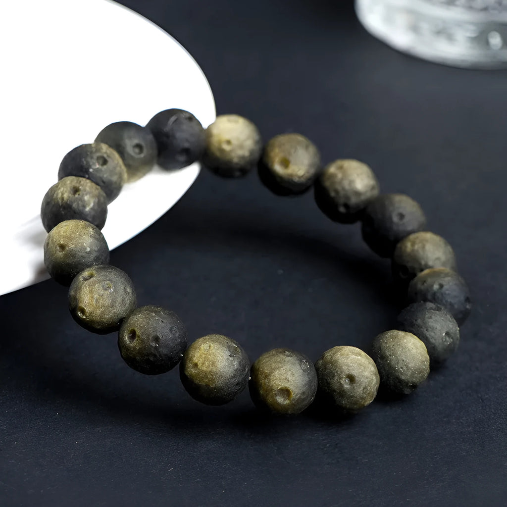 Close-up of a natural obsidian crater ball bracelet with grinding-treated beads on a wrist.