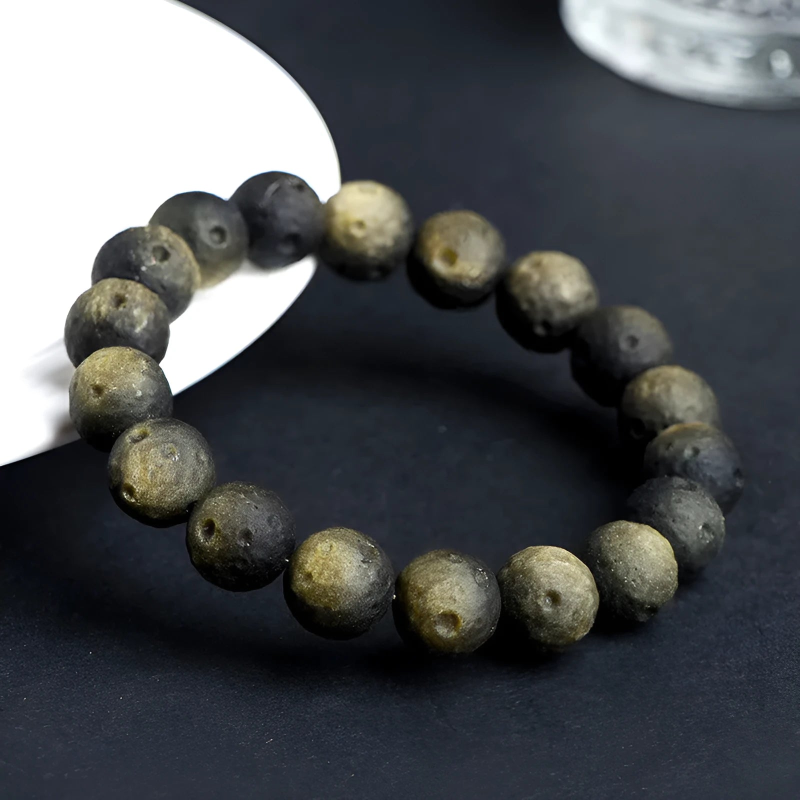 Close-up of a natural obsidian crater ball bracelet with grinding-treated beads on a wrist.