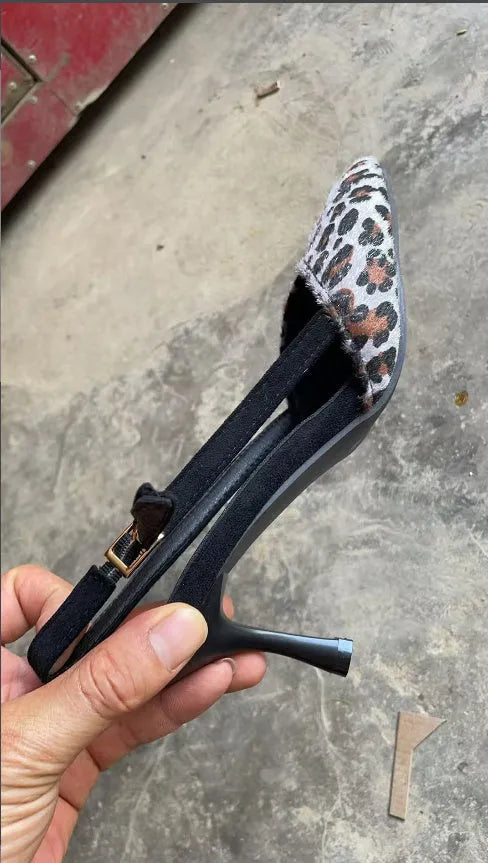 Leopard print women's suede sandals with a scattered pointed toe and high heel on a neutral background.