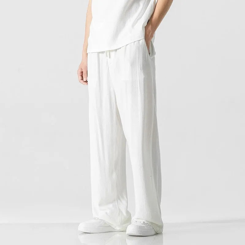 Man wearing beige straight-leg cropped linen trousers with a drawstring waist.