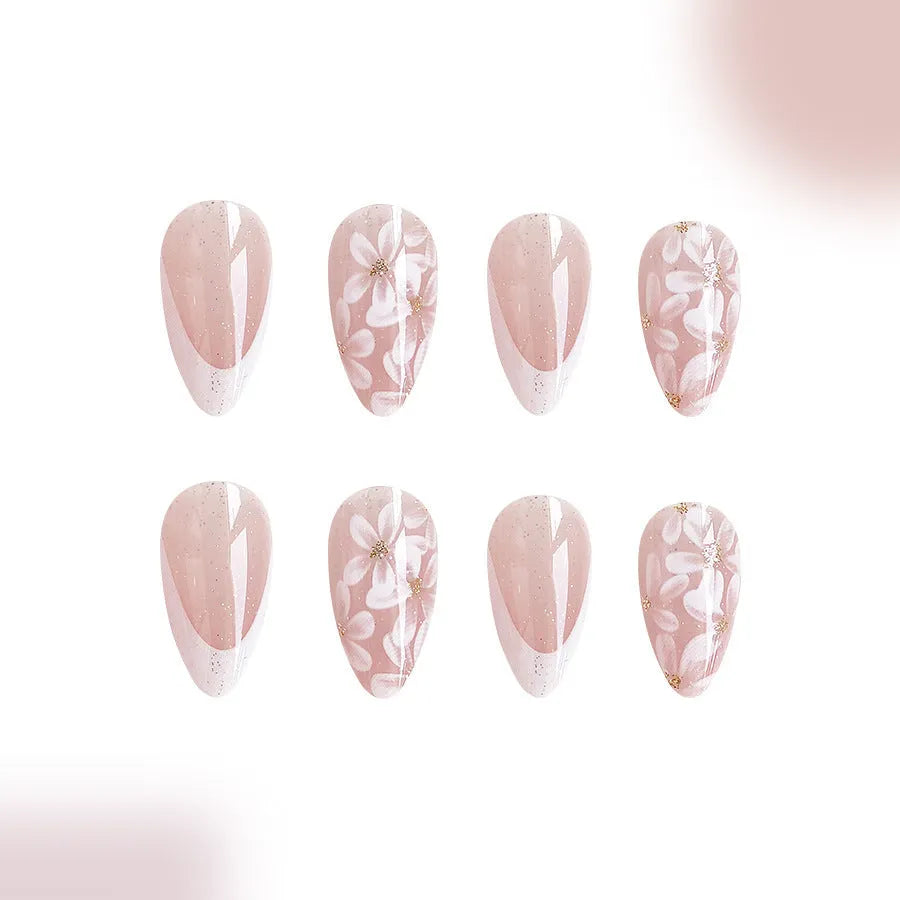 Short glossy almond-shaped false nails with French manicure style, white powder flowers, and glitter accents.