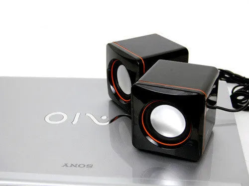Small square black USB-powered 2.0 computer speaker on a desktop.