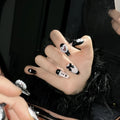 Hand-painted black and pink peach heart false nails with bow designs and cat's eye finish in four sizes