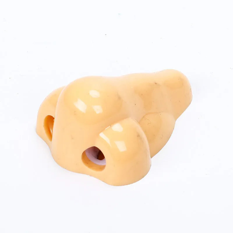 Flesh colour plastic geometry pencil sharpener with big nostril design on a white background.