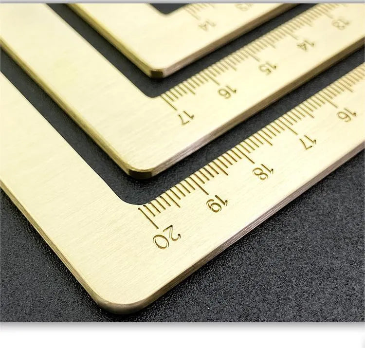 Square solid brass calligraphy paperweight with carved scale design on a wooden desk.