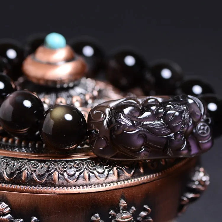 Polished crystal Pi Xiu bracelet with icy obsidian stone on wrist, showing geometric ethnic style.