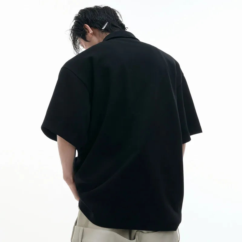 Man wearing a loose-fit black polo shirt with a deconstructed multi-collar and a geometric Giant Land Turtle graphic on the chest.