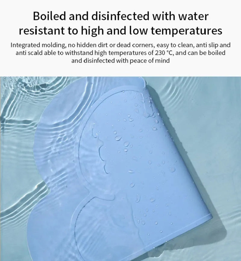 Blue silicone pet feeding mat shaped like a cat head on a wooden floor.