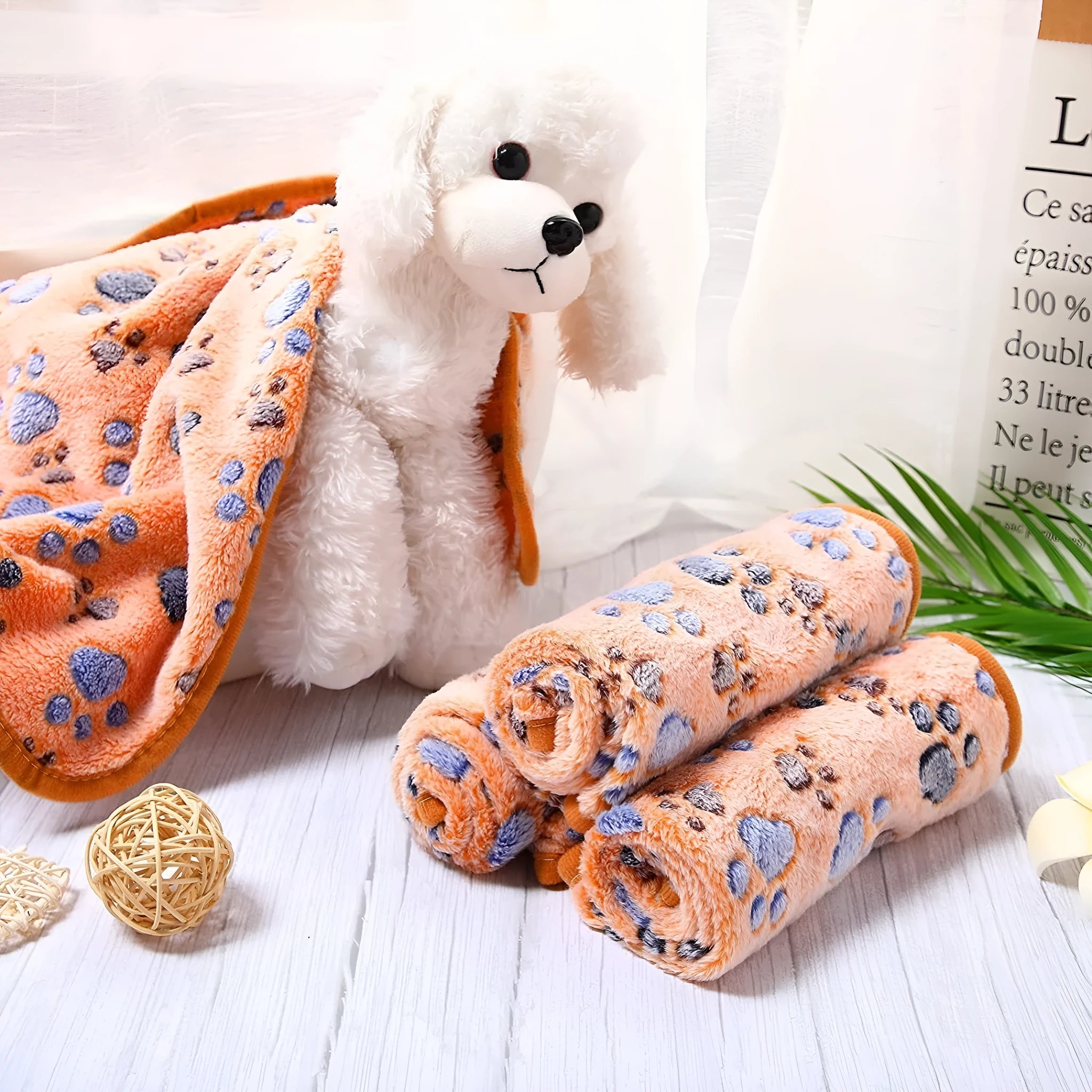 Soft coral fleece dog blanket with paw print design shown in beige colour on a dog bed.