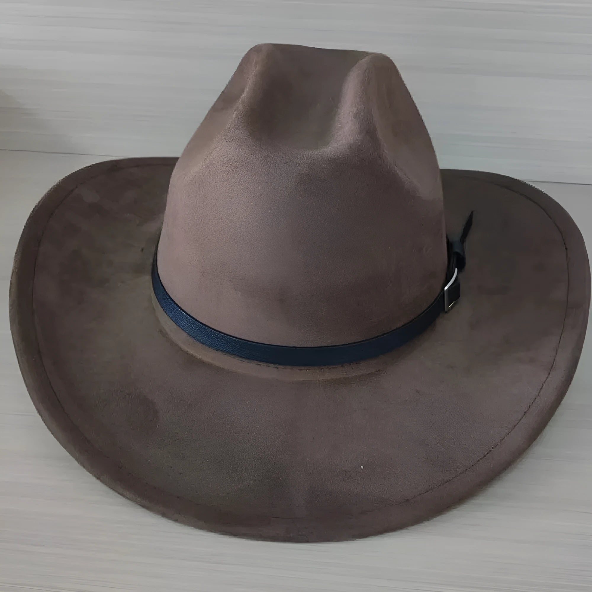 Brown leather velvet western cowboy hat with a curved brim on a wooden stand.
