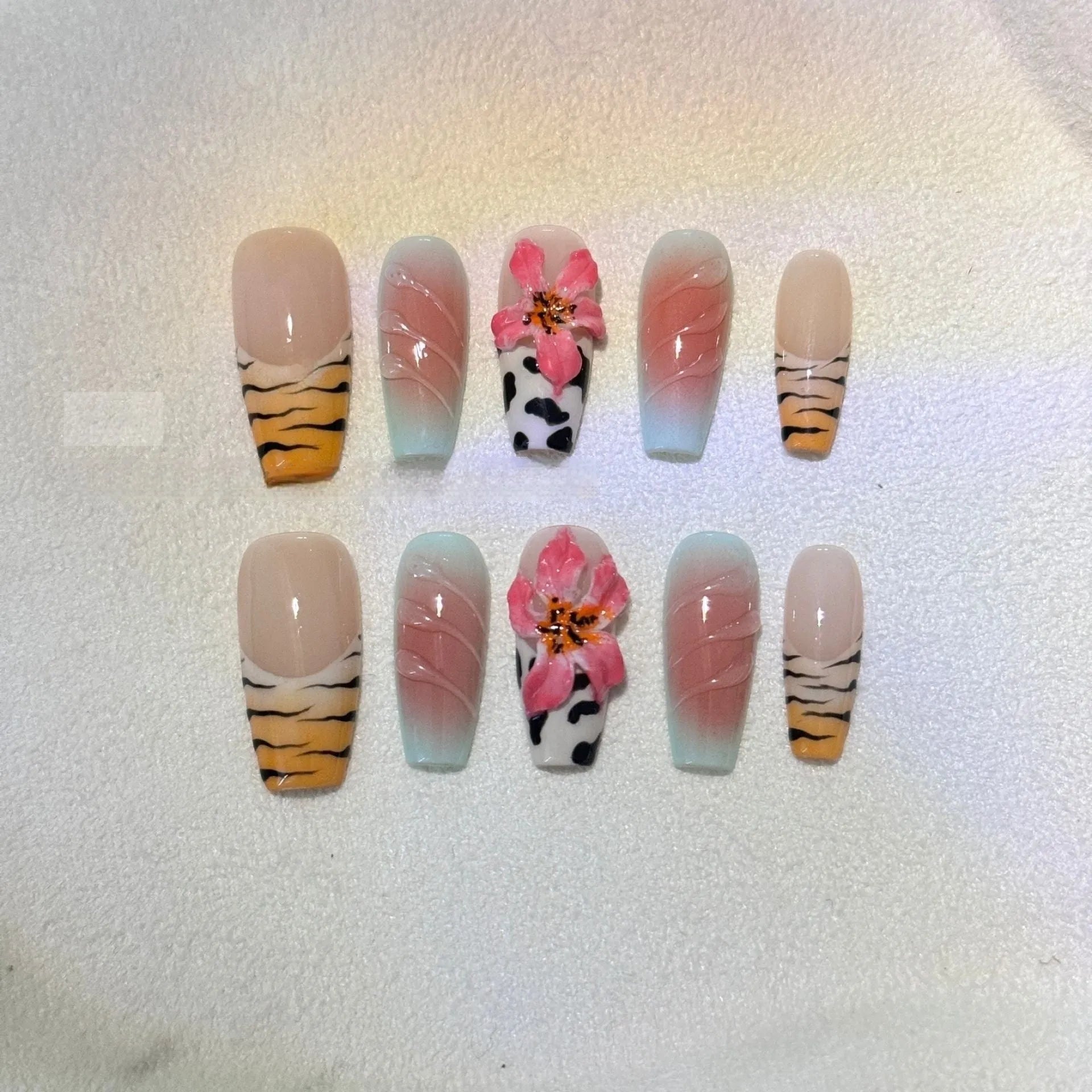 Zebra pattern and Lily hand carved nail art with flower and leopard print designs on a clear background.