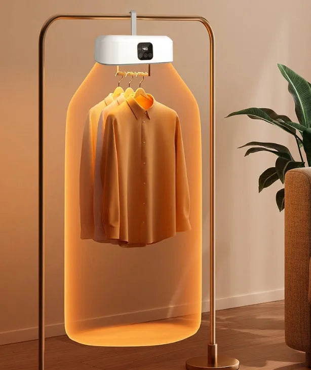 White cylindrical portable mini clothes dryer with remote control on a table.