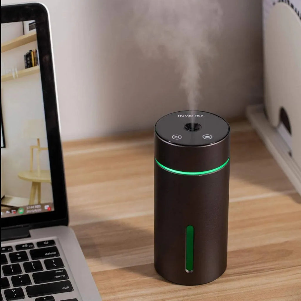 Compact black aluminium car humidifier and essential oil diffuser with USB cable on a desk.