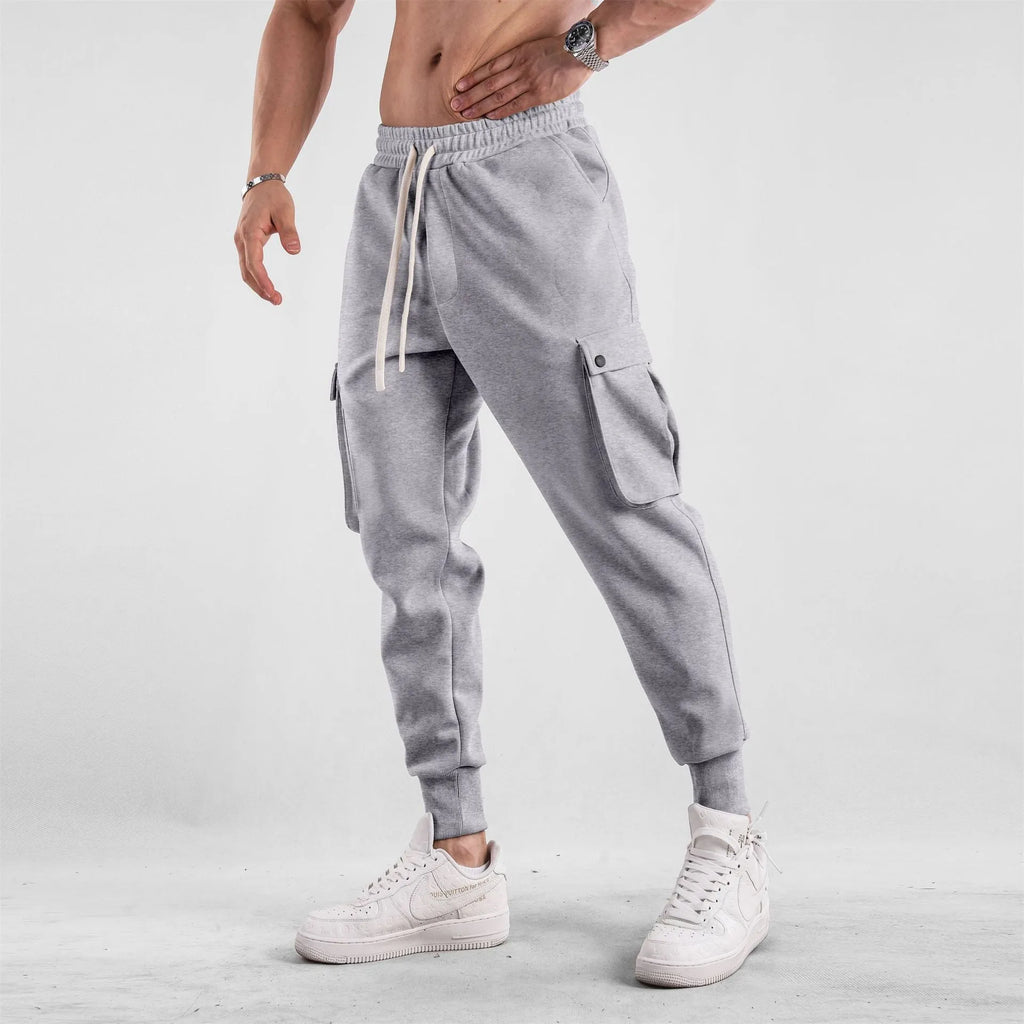 Men's loose cotton trousers with ankle ties and multiple pockets in a light grey colour