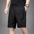 Man wearing loose black sports shorts made of polyester fabric, showing relaxed fit and elasticated waistband.