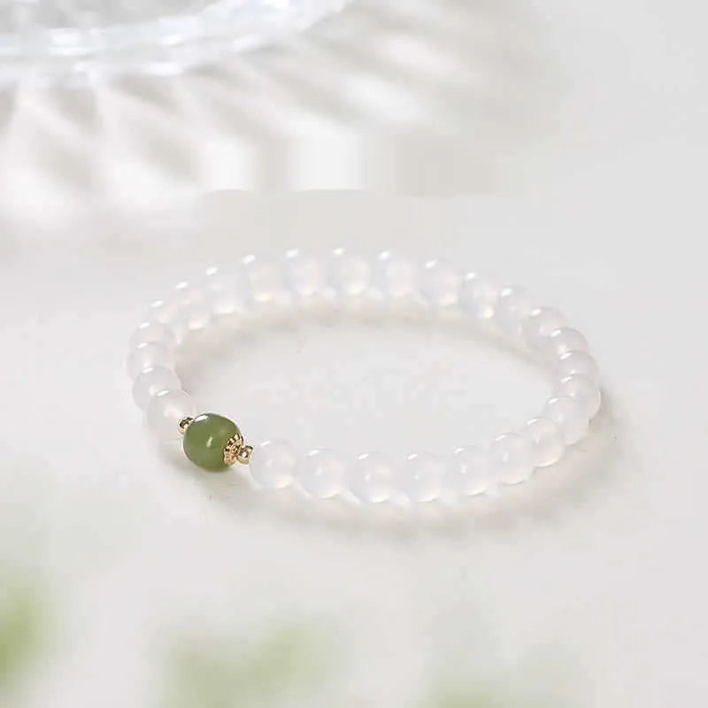 Handmade white agate and Hetian jade crystal bracelet with cinnabar accents on a wrist.