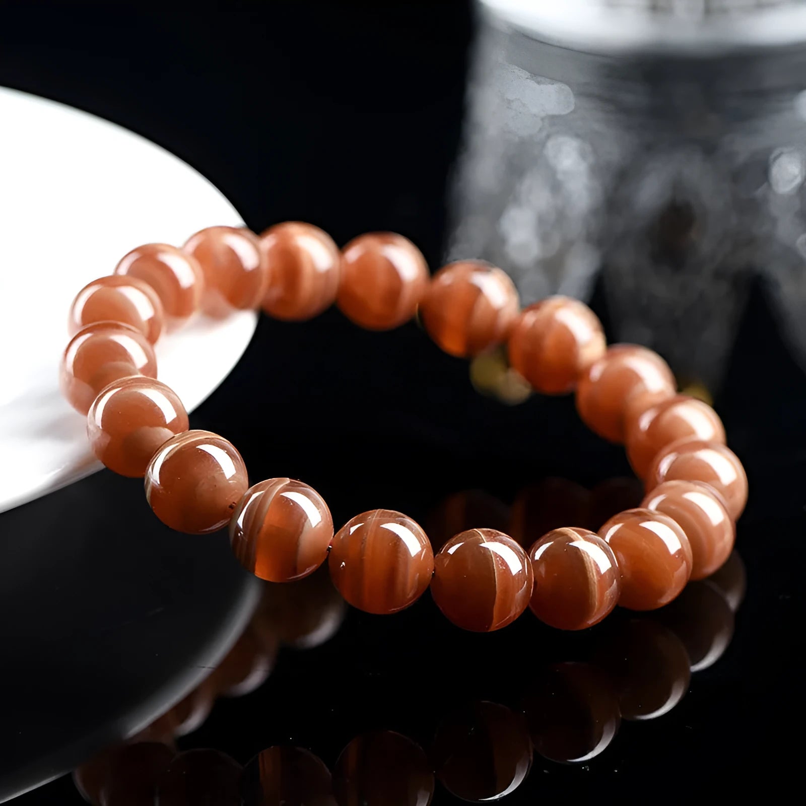 Natural old mine rhodochrosite round bead bracelet with ruyi design on a wrist.