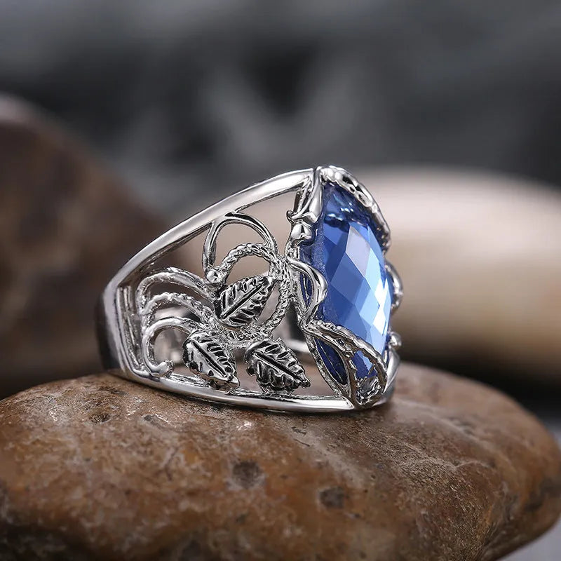 Blue crystal inlay horse eye-shaped geometric alloy ring for women on a plain background.