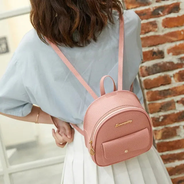 Small black PU leather ladies backpack with zipper, shown on shoulder