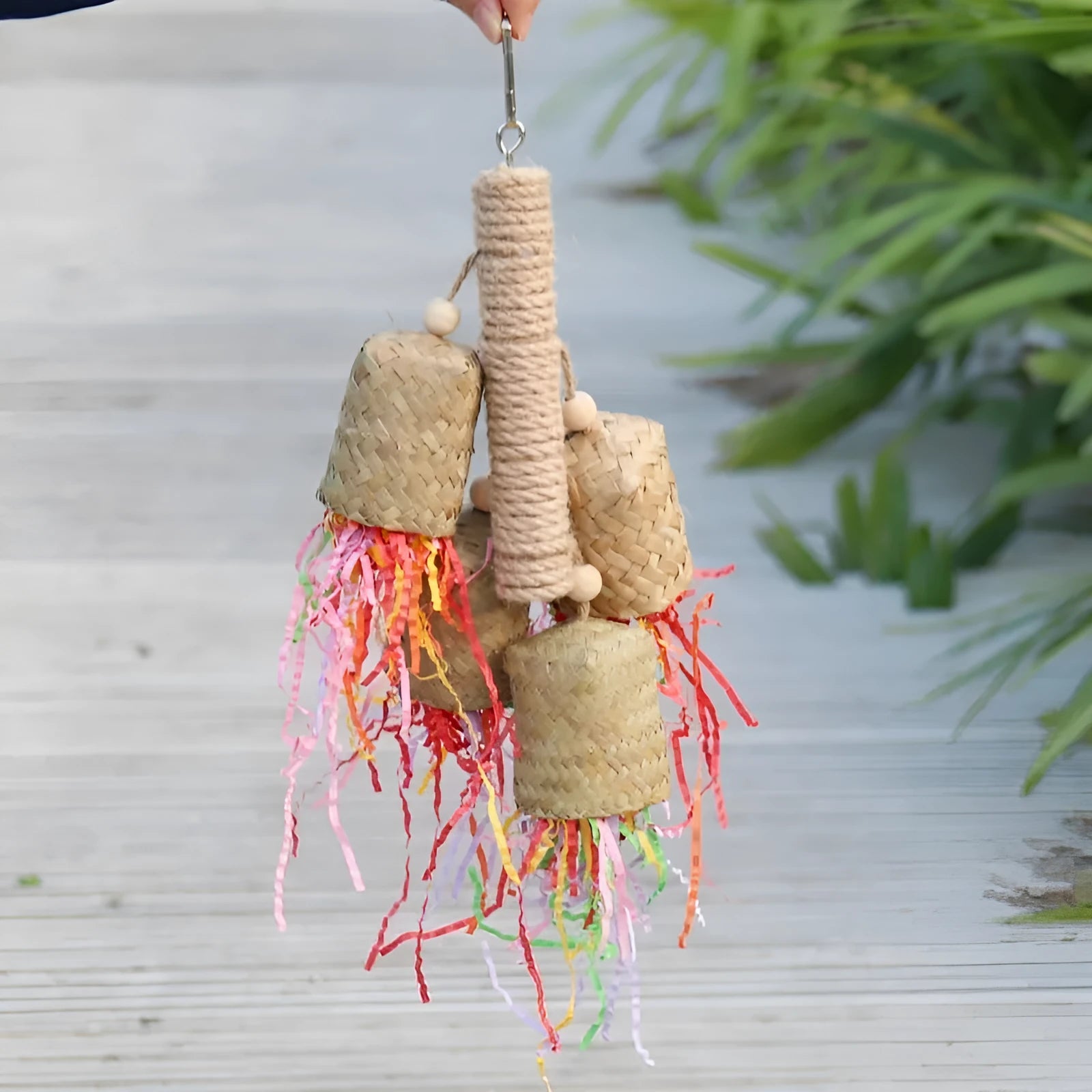 Parrot toy with wood pieces, sisal rope and colourful shredded paper strips hanging for bird enrichment