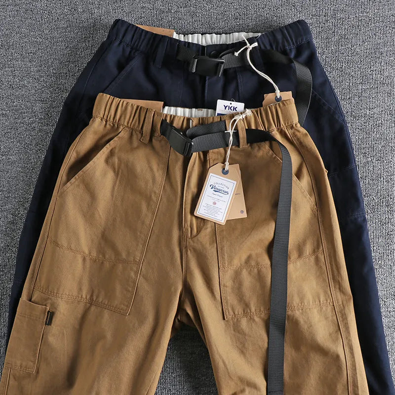 Men's khaki cotton work trousers with a flat buckle belt and zip fly, showcasing three-dimensional leg cutting.