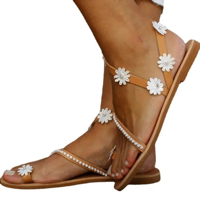 Brown women's flat sandals with decorative flowers and a herringbone toe shape on a rubber sole.