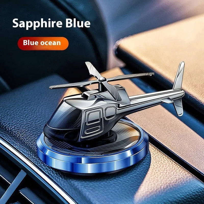 Metal solar helicopter car perfume ornament with rotating blades on a car dashboard.