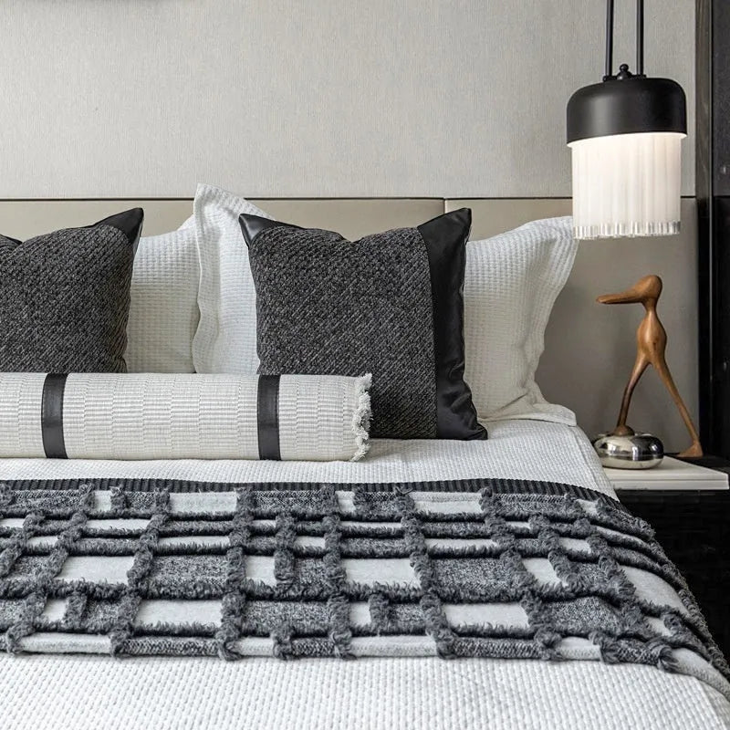 Modern grey and white plaid bed runner blanket set with leather round pillow on a bed