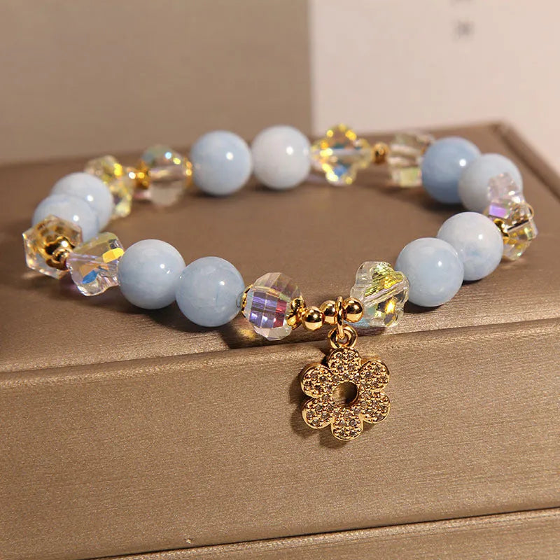 Women's aquamarine crystal bracelet with a four-leaf clover charm and pearl accents on a band.