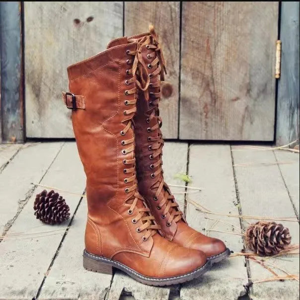 Black chunky heel high leg boot with round toe and low rubber sole on a plain background.