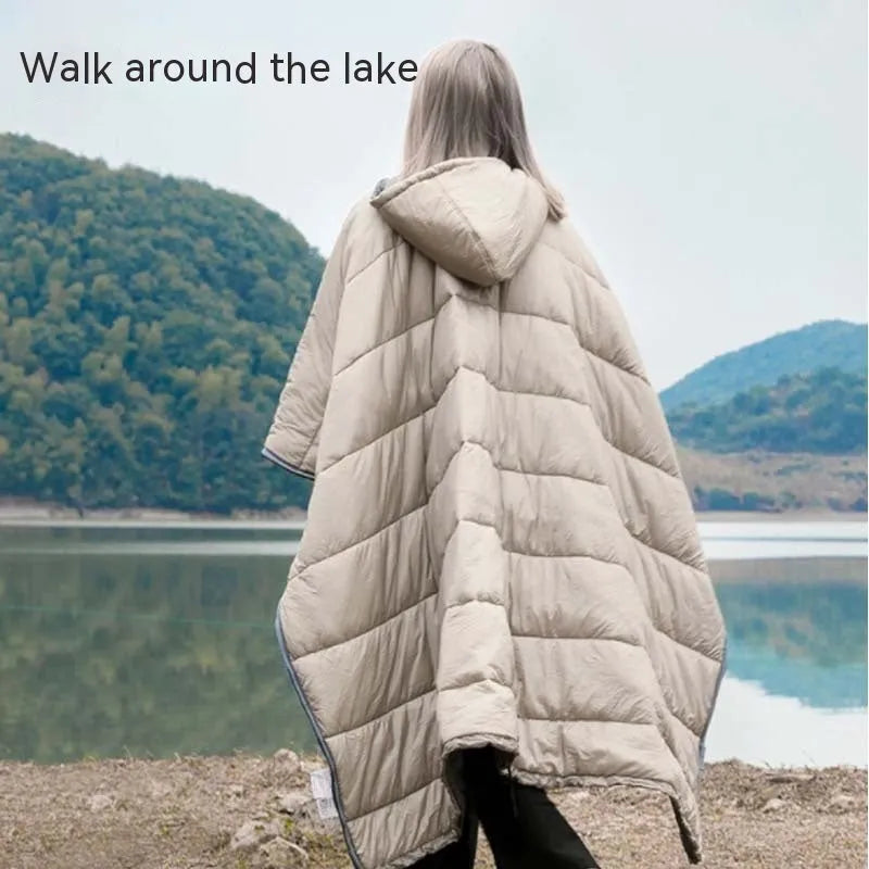 Adult wearing a gray hooded outdoor cloak that converts into a sleeping bag, shown laid flat at 200cm x 140cm.