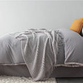 Small light grey polyester nap blanket folded, showing its size of 127 by 170 centimetres.
