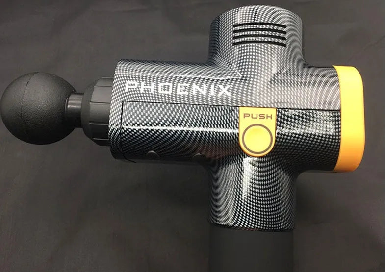 Black fascia massage gun with four different coloured attachment heads on a table.