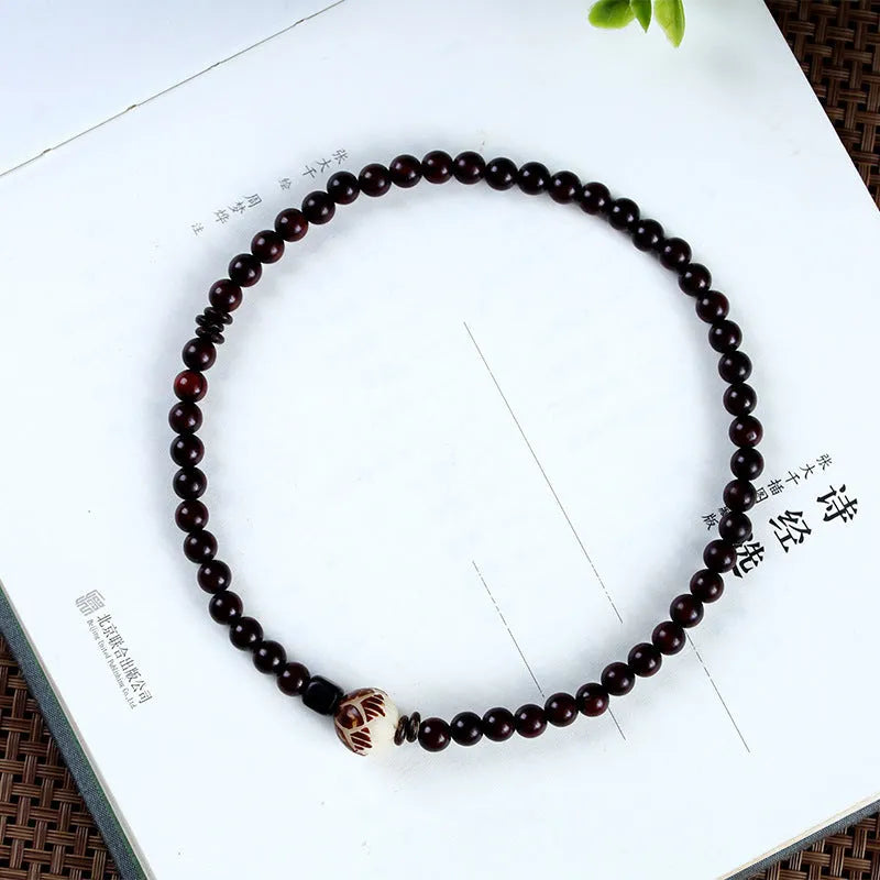 Rosewood bracelet with floral beads and circle pendant options on wooden background