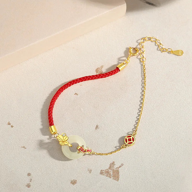 Close-up of a women's retro bracelet with a Hetian Jade stone, red cord, and a gold Koi fish safety buckle on a 925 silver chain.