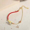 Close-up of a women's retro bracelet with a Hetian Jade stone, red cord, and a gold Koi fish safety buckle on a 925 silver chain.