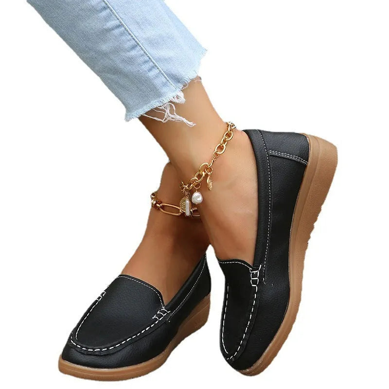 Women's black PU leather slip-on loafers with round toe and car suture detailing on a flat rubber sole.