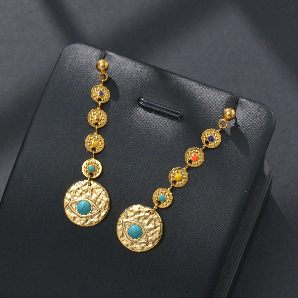 Three pairs of geometric stainless steel drop earrings showing Eight Awn Star, Eye, and Shell Sun designs