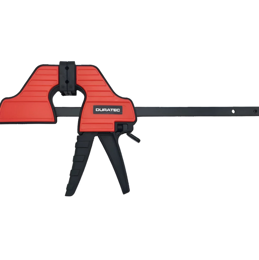 Black plastic quick release woodworking clamp with rubber jaws in multiple sizes on a workshop bench.