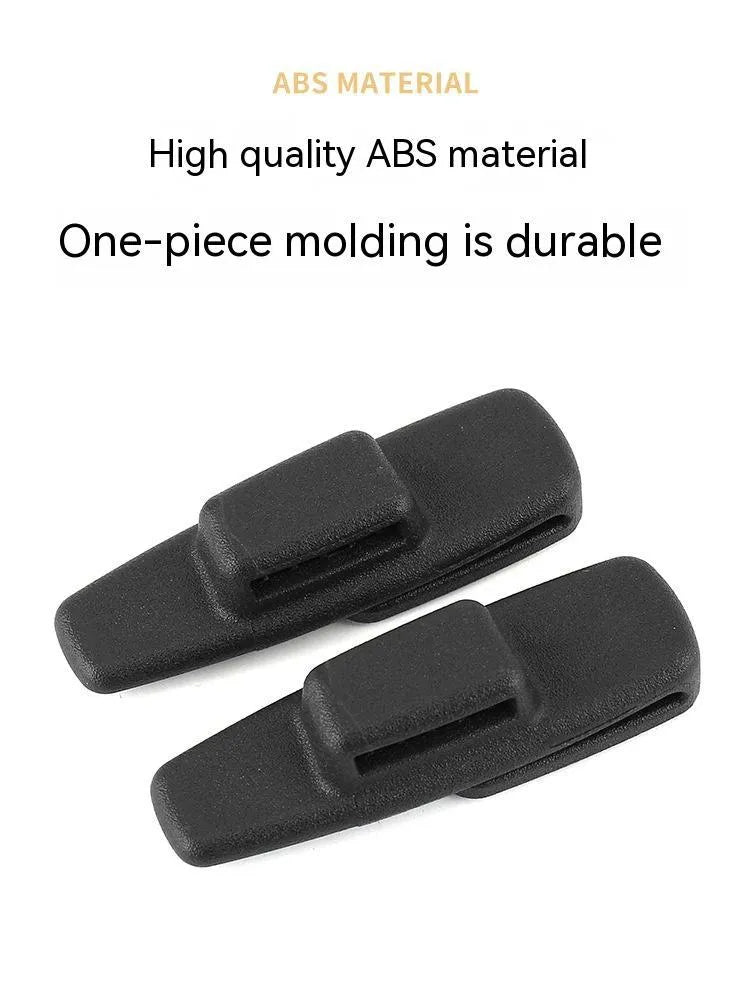 Two black ABS plastic universal car seat belt stopper clips on a grey background.