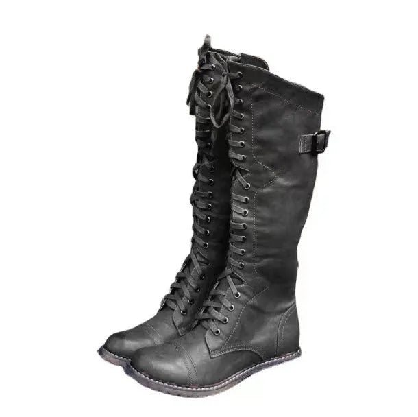 Black chunky heel high leg boot with round toe and low rubber sole on a plain background.