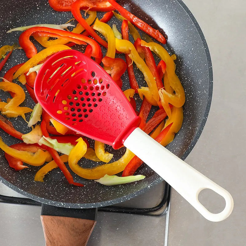 Red and black multifunctional plastic cooking spoon with serrated grinding edge and half-enclosed rice scoop head.