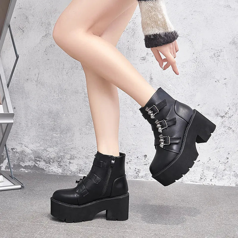 Black women's punk ankle boots with bat buckle detail, chunky heel, and side zipper.