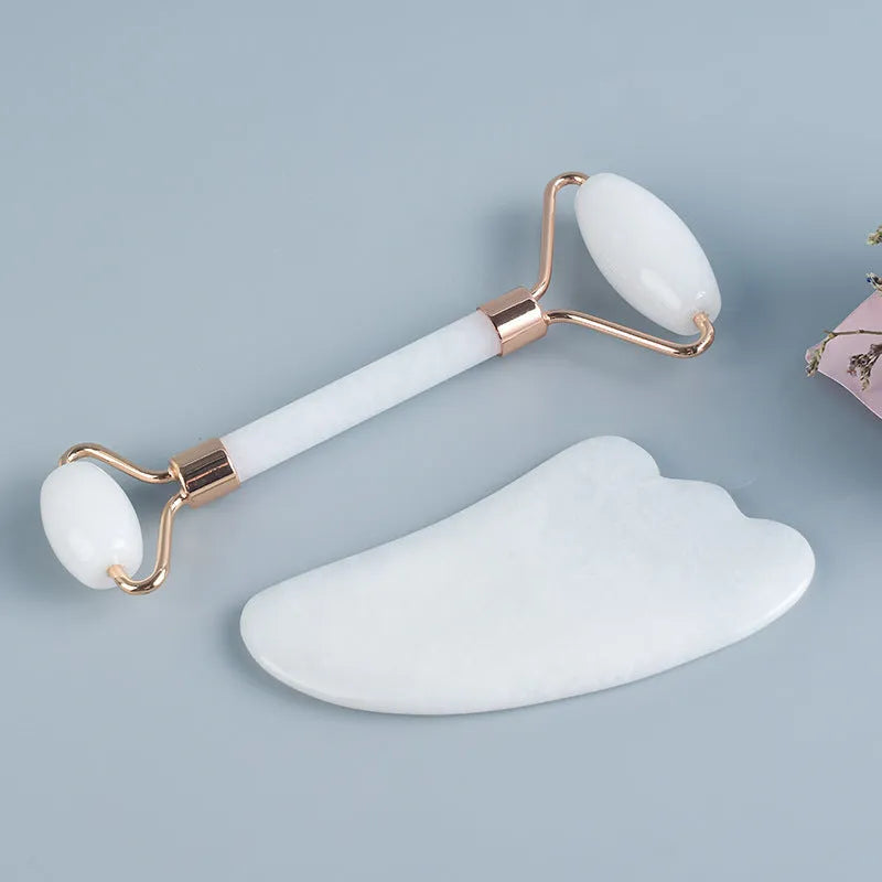 Natural white jade roller and gua sha scraping tool set presented on a wooden storage board.