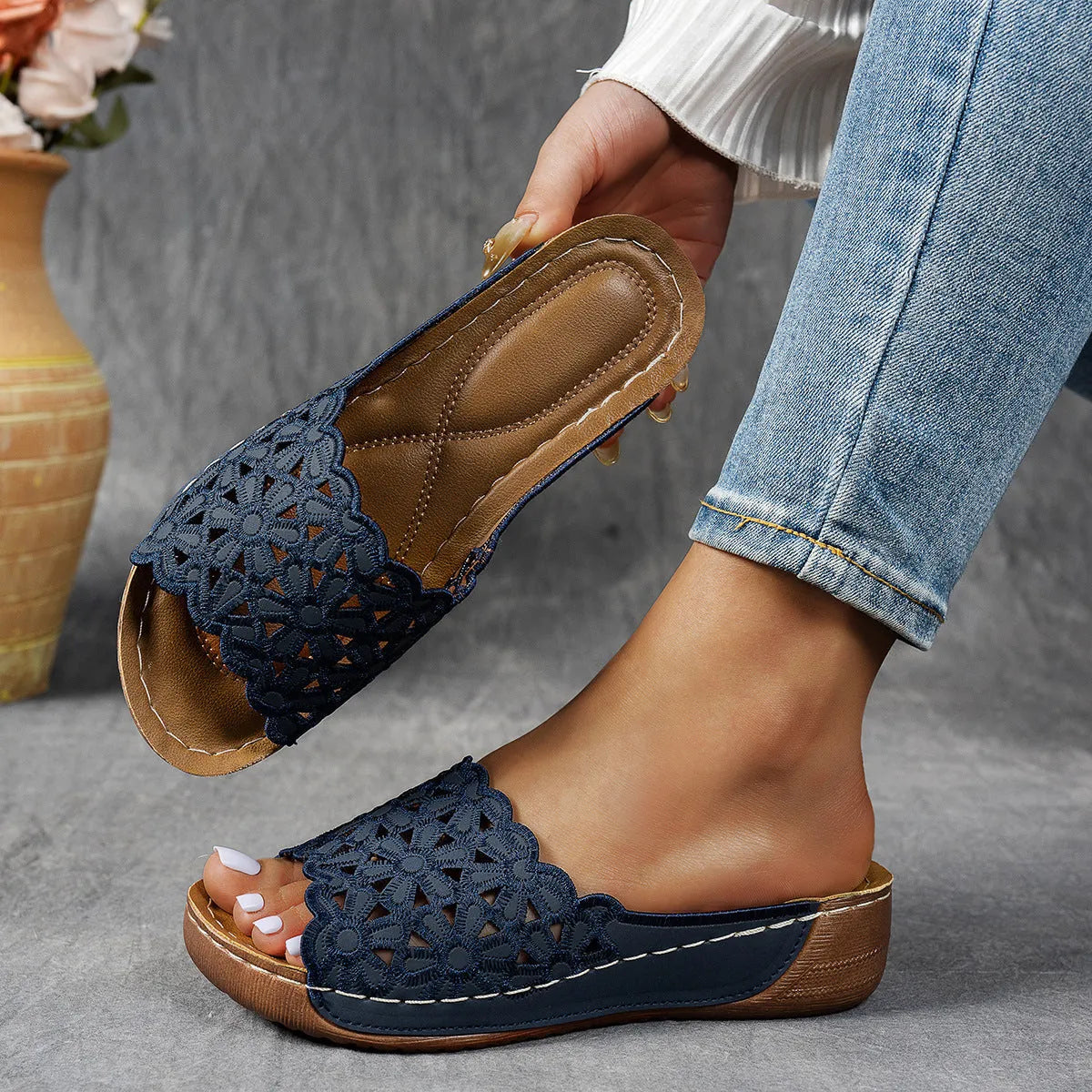Women's black wedge beach slippers with flower cutout design on the PVC upper and a rubber sole.