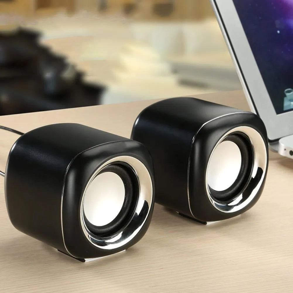 A pair of compact black wired desktop computer speakers with a 3.5mm audio cable.