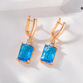 A pair of square-shaped gold-coloured earrings with a geometric design on a white background.