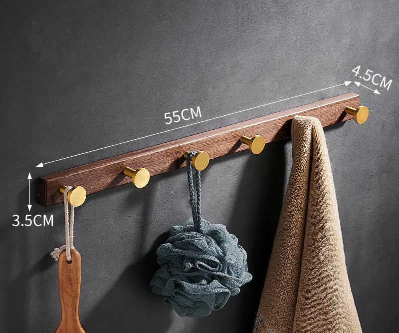 Black walnut wood hooks mounted on a perforated aluminium plate for bathroom towel hanging.