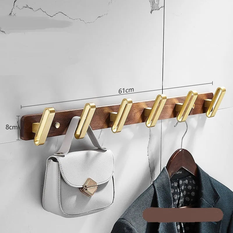 Black walnut wood hooks mounted on a perforated aluminium plate for bathroom towel hanging.