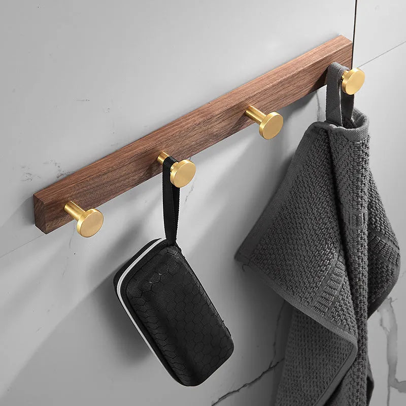 Black walnut wood hooks mounted on a perforated aluminium plate for bathroom towel hanging.